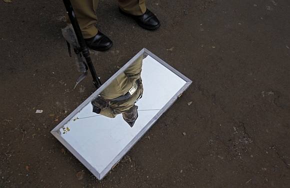 A policeman's reflection is seen in a mirror used to check vehicles for explosives outside the Bombay high court before the delivery of a judgement for Ajmal Kasab