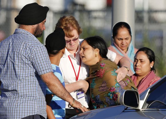 A distraught women is helped to a car outside the Sikh temple in Oak Creek, Wisconsin, after seven people lost their lives in a shooting incident