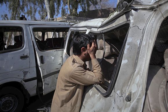 A man weeps next to a damaged vehicle after it was hit by a bomb attack in the outskirts of Peshawar, northwest Pakistan