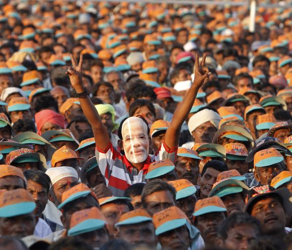 A supporter Narendra Modi wears his mask during a campaign rally in Gujarat's Pavagadh town
