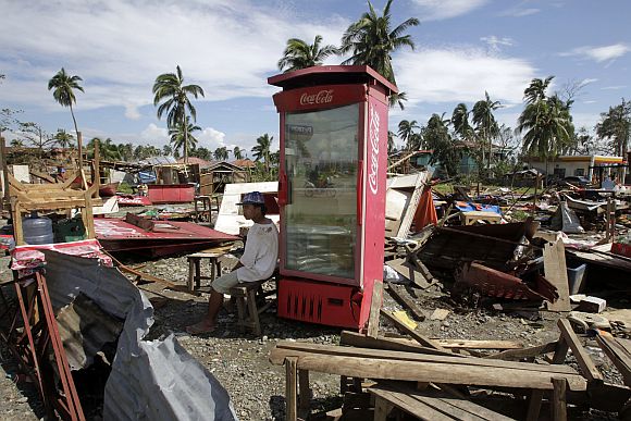 A vendor sits next to a Coca Cola refrigerator amidst destroyed food stalls after Typhoon Bopha hit Compostela Valley, southern Philippines December 5, 2012