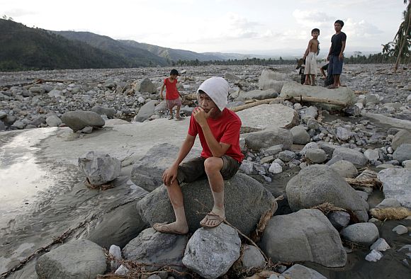 Villagers gather on a destroyed highway littered with rocks and debris after flashfloods brought by Typhoon Bopha in Compostela Valley in southern Philippines