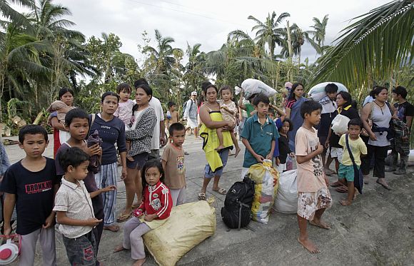 Villagers wait to be evacuated after their homes were swept away by flash floods brought by typhoon Bopha in Compostela Valley, southern Philippines