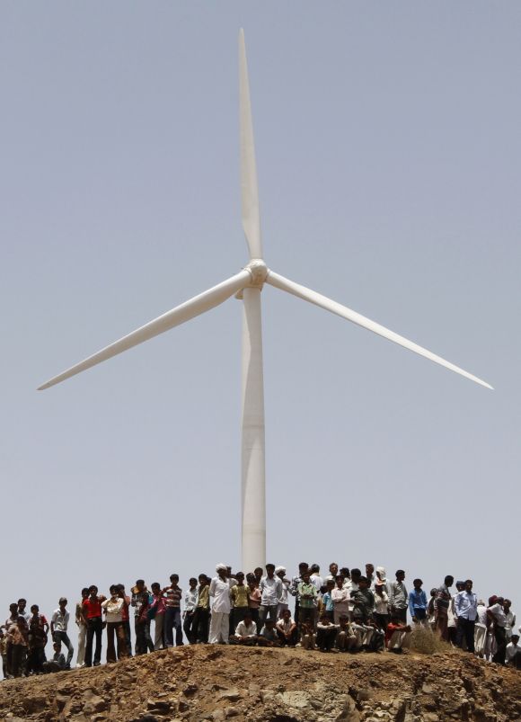 Villagers stand under a power generating windmill turbine at Kalasar village in Gujarat.