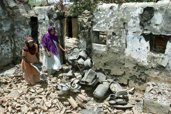 Muslim women Mariba and Zarina Bibi rummage through the debris of their house in Kadwal village in Gujarat on May 12, 2002