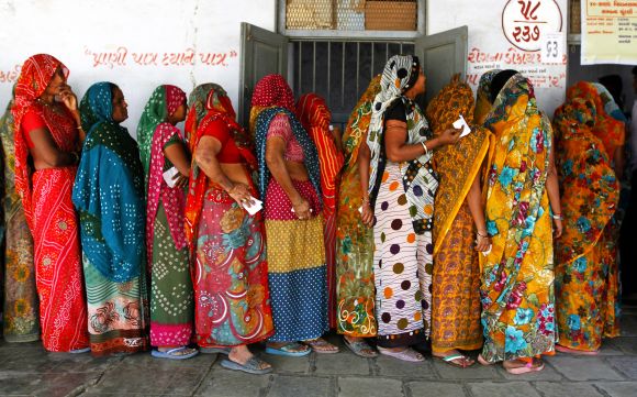 Women stand in a queue to cast their ballots outside a polling booth in Sanand on Thursday
