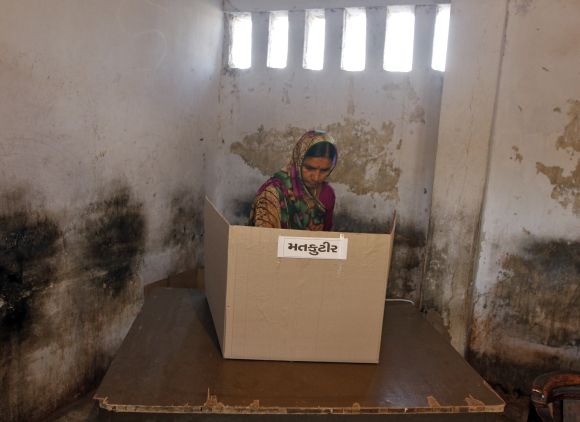 A woman casts her vote at a polling booth in Sanand on Thursday