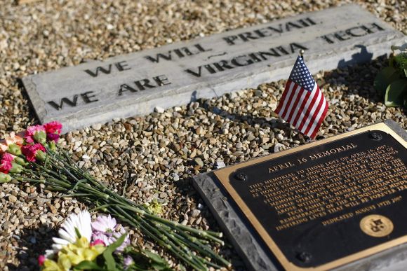 A small United States flag is displayed along with flowers at a plague located in the April 16 memorial on the campus of Virginia Tech in Blacksburg