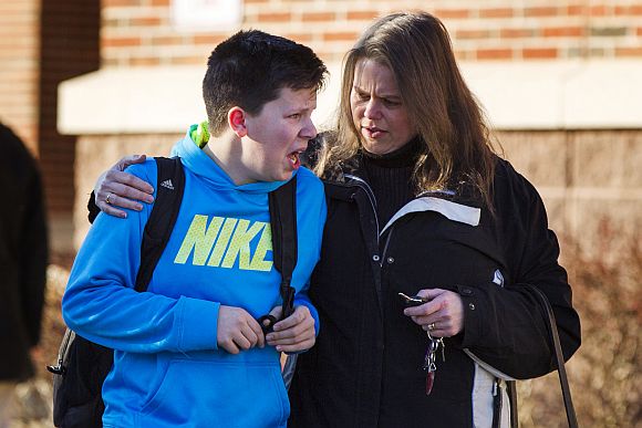 A boy weeps as he is told what happened after being picked up at Reed Intermediate School following a shooting at Sandy Hook Elementary School in Newtown, Connecticut, December 14