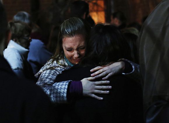 People grieve outside the overflow area of a vigil at the Saint Rose of Lima church in Newtown, Connecticut