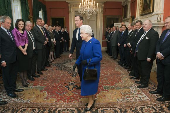 Queen Elizabeth walks with Prime Minister Cameron as members of the cabinet watch at Number 10 Downing Street