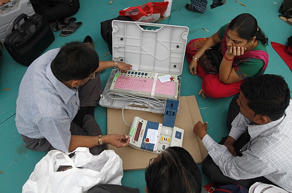 A polling official checks a tag on an EVM at a distribution centre in Sanand, the western