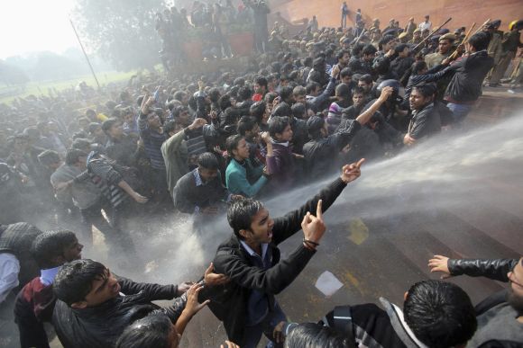 Demonstrators shout slogans as police use water cannons to disperse them at Raisina Hills during a protest rally in New Delhi
