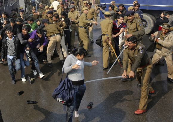 A policeman wields his baton against a female demonstrator at Raisina Hills in New Delhi