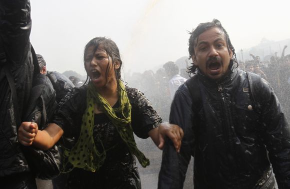 Demonstrators shout slogans as they are hit by police water cannon near the Rashtrapati Bhavan