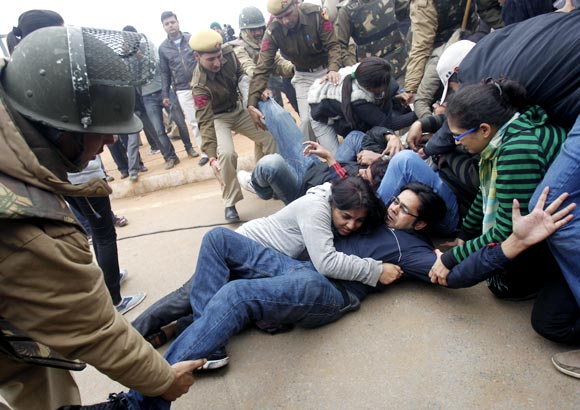 Demonstrators huddle as police try to detain them in front of the India Gate