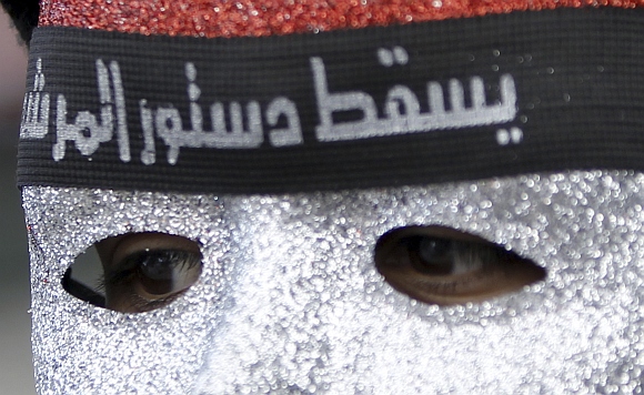 A protester against Egyptian President Mohamed Mursi wears a mask with the colours of Egypt's national flag and a headband at Tahrir Square in Cairo