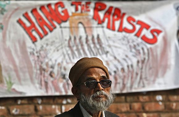 A demonstrator sits in front of a banner as he takes part in a protest in New Delhi