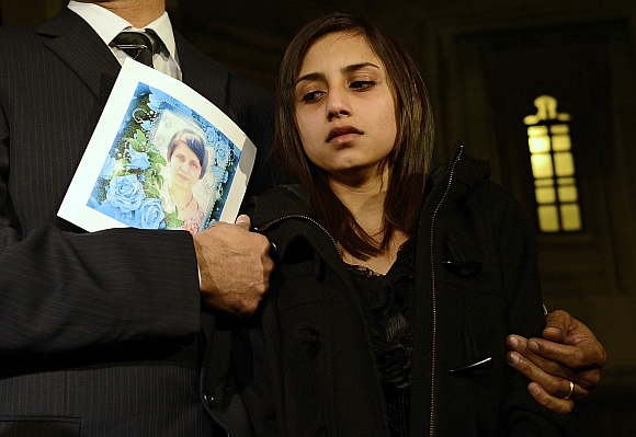 Lisha Barboza reacts as she stands with her father Ben while he holds a picture of his wife, nurse Jacintha Saldanha, as they leave the Houses of Parliament in London