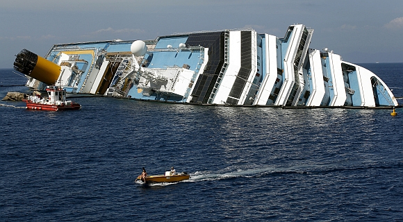A boat sails past capsised cruise liner Costa Concordia near the harbour of Giglio Porto