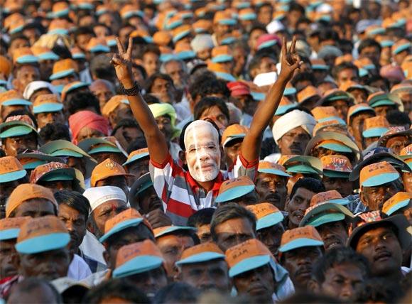 A supporter of Gujarat's Chief Minister Narendra Modi wears a mask during an election campaign rally at Pavagadh in Gujarat