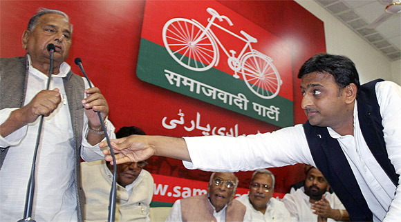 Uttar Pradesh Chief Minister Akhilesh Yadav adjusts the microphone for his father, the Samajwadi Party President Mulayam Singh Yadav, at the party headquarters in Lucknow