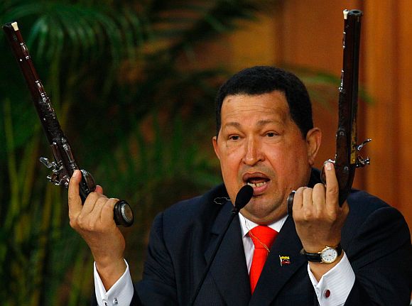 Venezuelan President Hugo Chavez shows the pistols of independence hero Simon Bolivar during a ceremony to mark the his birthday in Caracas