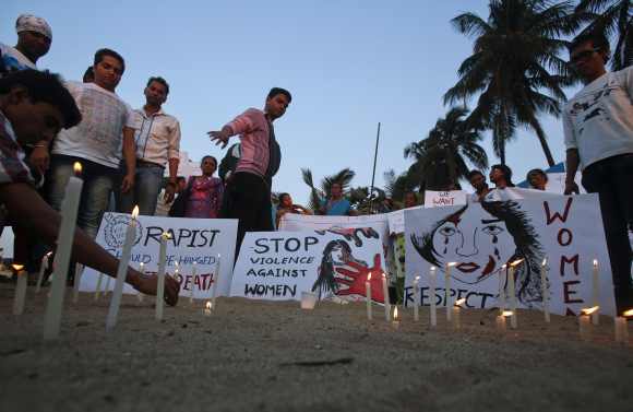 Demonstrators light candles and place placards in the sand during a protest rally in solidarity with a rape victim from New Delhi in Mumbai