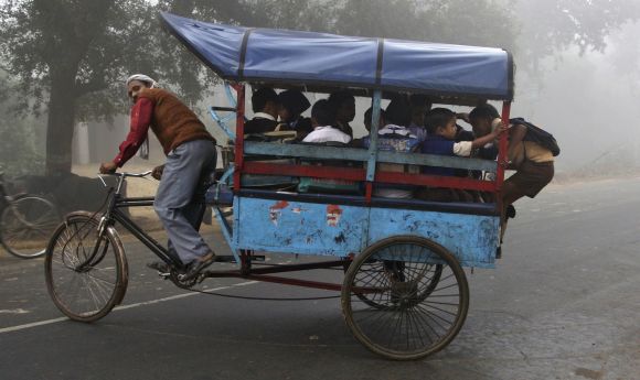 A man pedals his trishaw carrying school children in Allahabad