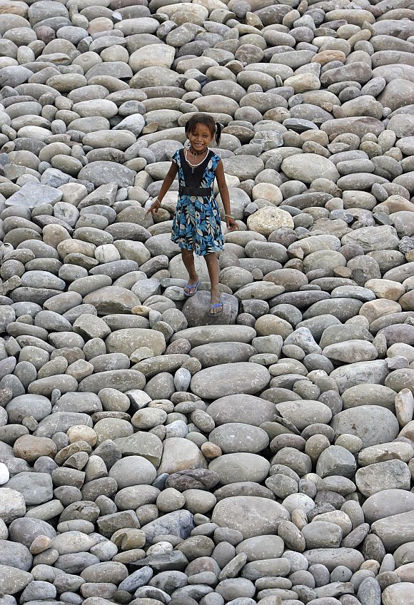 A girl smiles as she walks on the Tawi riverbed in the outskirts of Jammu.