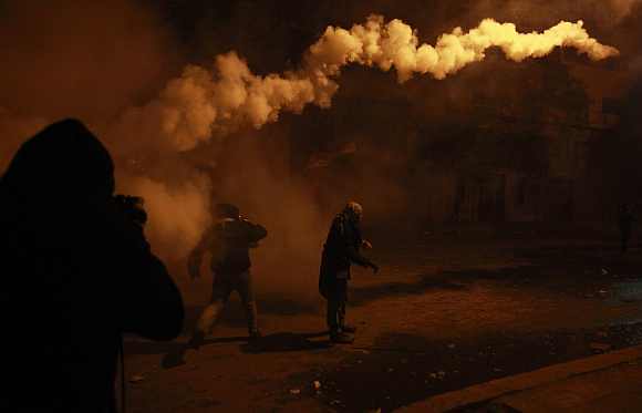 A protester returns a gas canister during clashes with security forces in Cairo on February 2