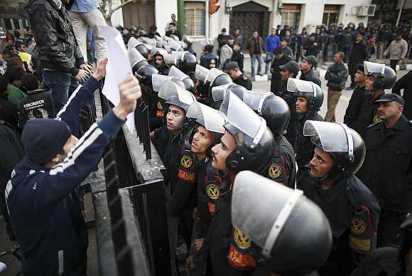 Riot police look at a banner held by a protester during a protest condemning the killings that happened on Wednesday at Port Said stadium