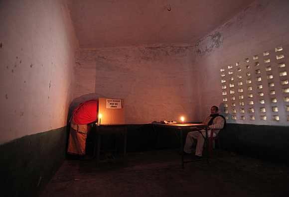 A priest  casts his vote as a polling officer watches at a polling station in Ayodhya