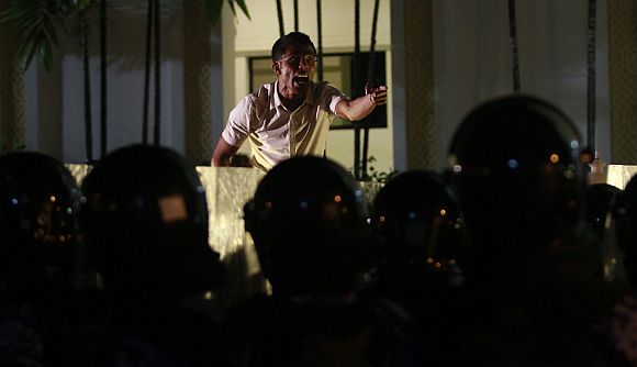 A supporter of Mohamed Nasheed shouts slogans in front of a police officer during a protest in Male on Sunday night