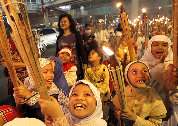 Children march through a street carrying torches to mark the end of Ramadan in Jakarta