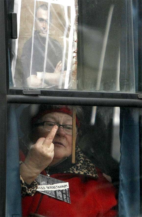 A protester gestures from the window of a police bus in front of the court building in Moscow