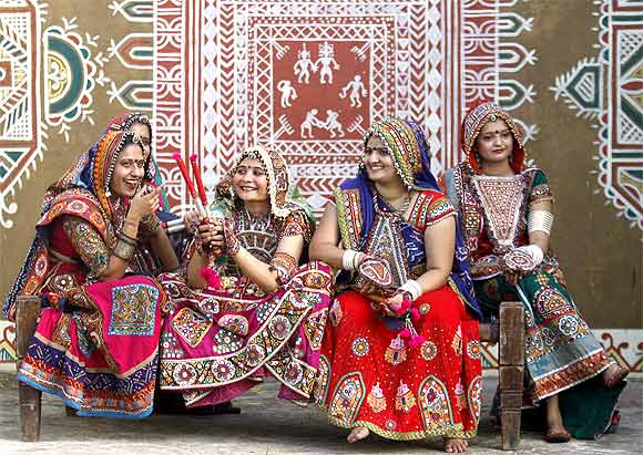 Dancers dressed in traditional attire sit on a cot during Navratri in Ahmedabad