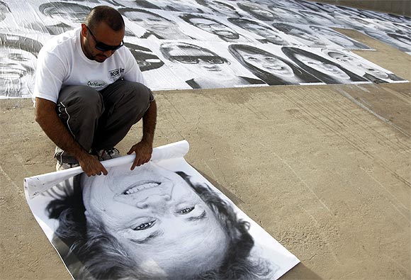 A volunteer rolls up a photograph during an open-air exhibition at Rio Bravo, in Ciudad Juarez, Mexico