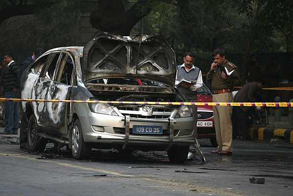 Police and forensic officials examine a damaged Israeli embassy car after an explosion in New Delhi