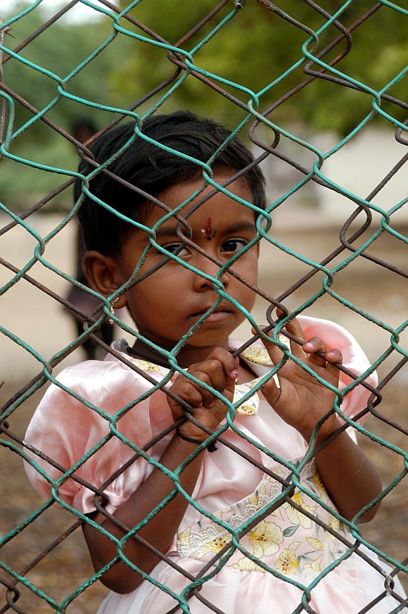 A Sri Lankan refugee girl stands behind the gate of the Mandapam refugee camp in the Ramanathapuram district, about 620 km from Chennai