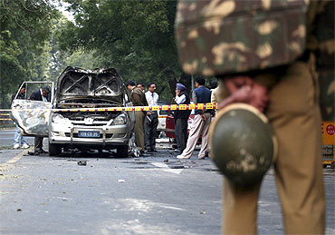 Police and forensic officials examine the damaged Israeli embassy car in New Delhi