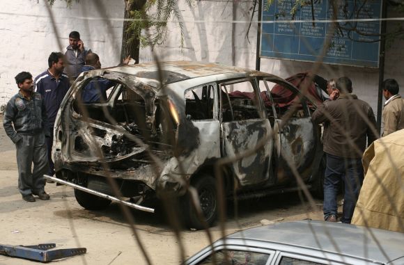 Police cover a damaged Israeli embassy car before it was towed away from a police station to another police station in New Delhi