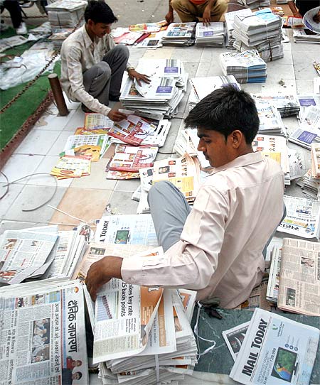 Distributors sort through newspapers before selling them in Noida, UP