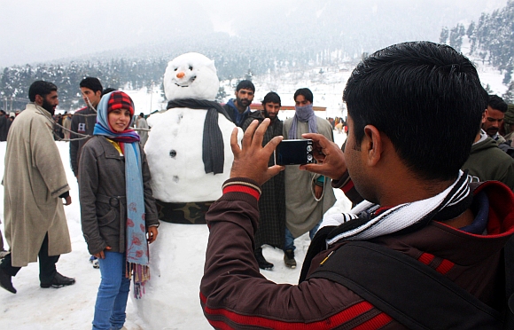 A tourist poses with a snowman