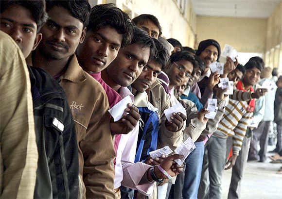 oters display their voter identity cards as they wait for their turn to cast their ballots at a polling station
