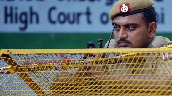 A policeman keeps guard from behind a barricade outside the high court after a bomb blast in New Delhi