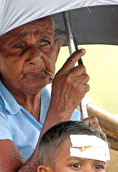 A file photo of an elderly woman waiting for transportation with a boy as they flee from their houses  in Trincomalee