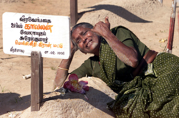 A mother cries on top of her son's grave at a cemetary in Mullathivu
