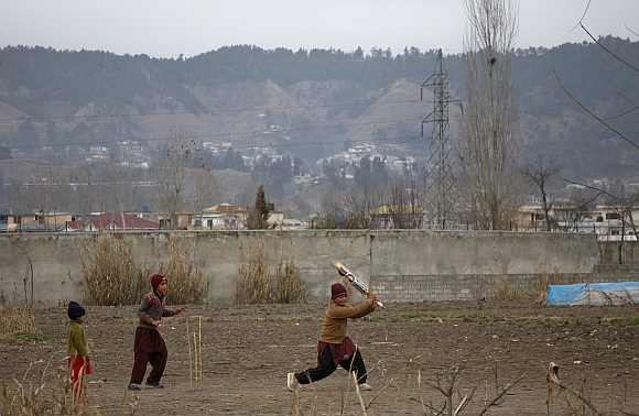 Children play cricket near the boundary wall of the building where bin Laden was killed, after it was demolished in Abbottabad