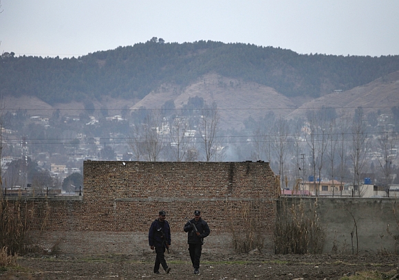 Policemen walk past the boundary wall of the building where bin Laden was killed after it was demolished in Abbottabad